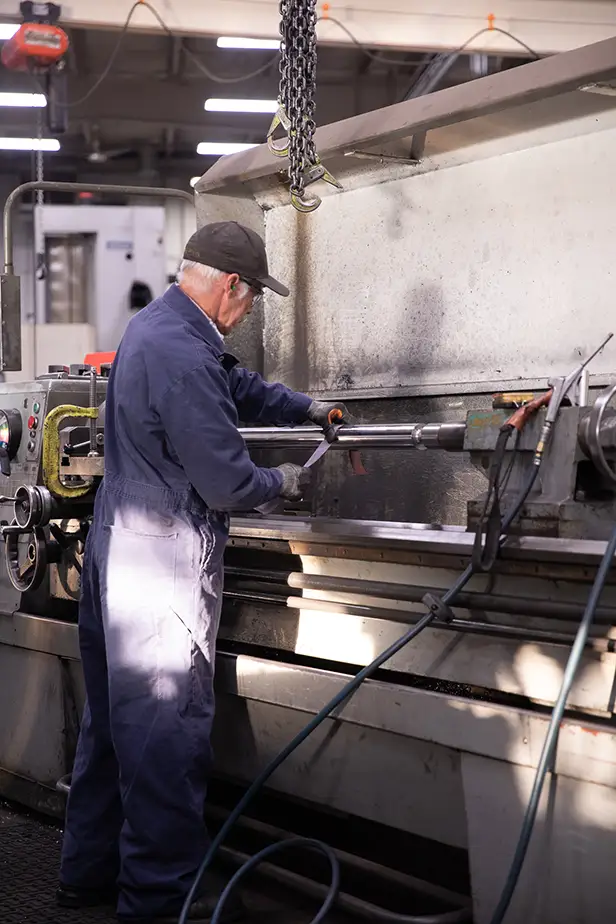 Machine shop technician polishing hydraulic cylinder